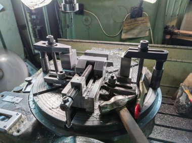 classic milling machine turntable with vise and claps fixture, hammer and paint brush, closeup