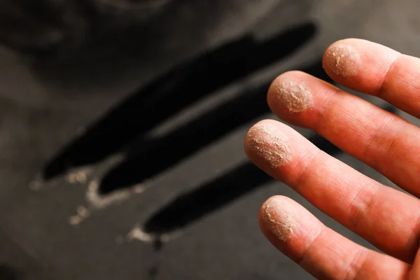 caucasian hand with dust on finger tips after touching black dusty surface, closeup with selective focus