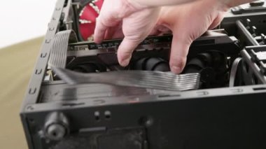 caucasian hand inserting new big black triple fan graphics card into black pc case during upgrade or assembly process