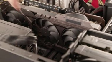 caucasian hands spinning fans of large air cooled computer graphic card inside personal computer ATX tower case