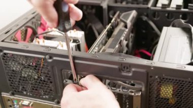 caucasian hands screwing in graphics card in pc case with screwdriver during installation or hardware upgrade