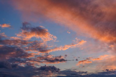 Cumulus clouds on evening sky backlit with sunset. Captured with 70mm lens on 35mm full-frame sensor camera.