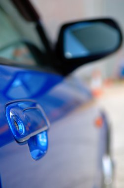 Right side mirror of shiny blue car