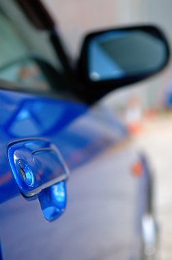 Right side mirror of shiny blue car