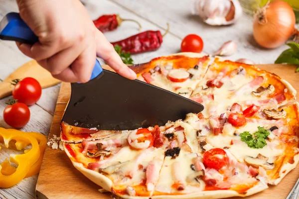 Cutter cuts a fresh pizza — Stock Photo, Image