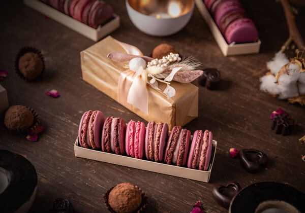 Sweet gift box of pink macarons on dark wooden background
