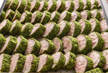 Yeşil bitki kabuğuyla kaplı domuz filetosu parçaları.