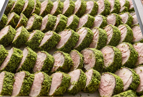 Yeşil bitki kabuğuyla kaplı domuz filetosu parçaları.