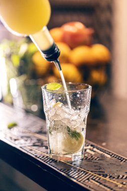 Profesyonel erkek barmen barın üstünde bardağa şurup döküyor. 