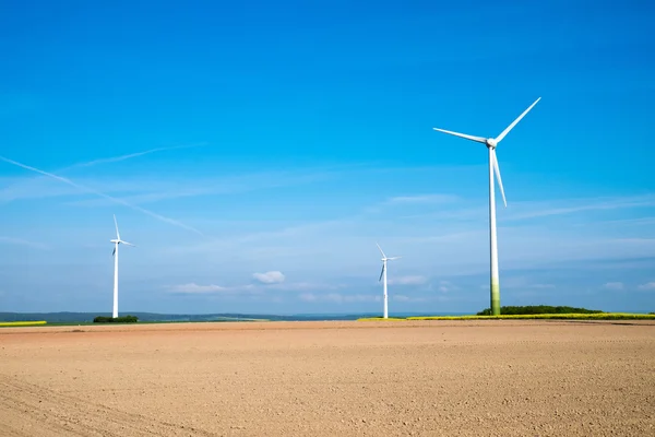 Windwheels behind a barren field — Stock Photo, Image