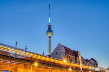 Berlin'de ünlü Televizyon Kulesi bir hareket bulanık banliyö treni ile alacakaranlıkta