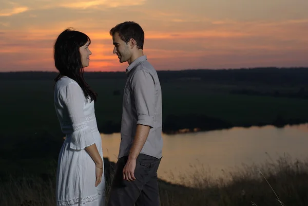 Couple at sunset and lake — Stock Photo, Image