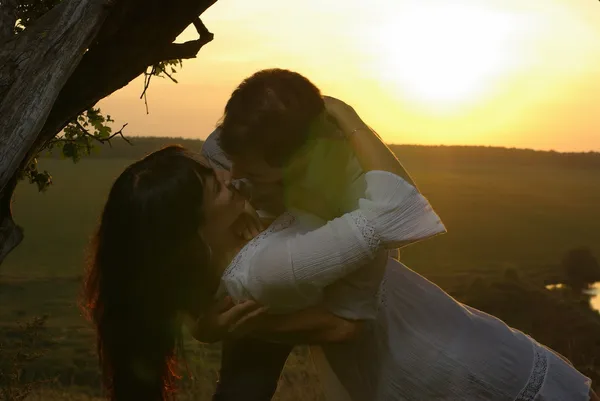 在日落时分在树下接吻的夫妇 — 图库照片