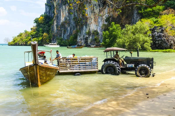 タイの熱帯島にトラクターの海岸にボートからの製品の読み込み — ストック写真