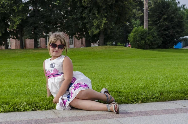 Une petite fille en robe d'été se promène dans le parc — Photo