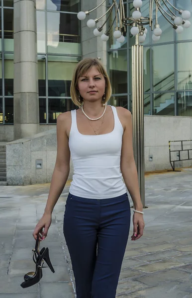 A young woman walks barefoot businessman after a hard day on the background of a modern business center — Stock Photo, Image