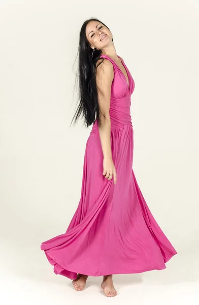 ローネックのピンクのドレスで長い髪と美しいブルネットの少女考え込むように立っている裸足で、半分になっています。 — ストック写真