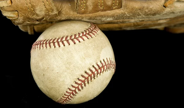 Uma bola de beisebol em uma luva com fundo preto — Fotografia de Stock