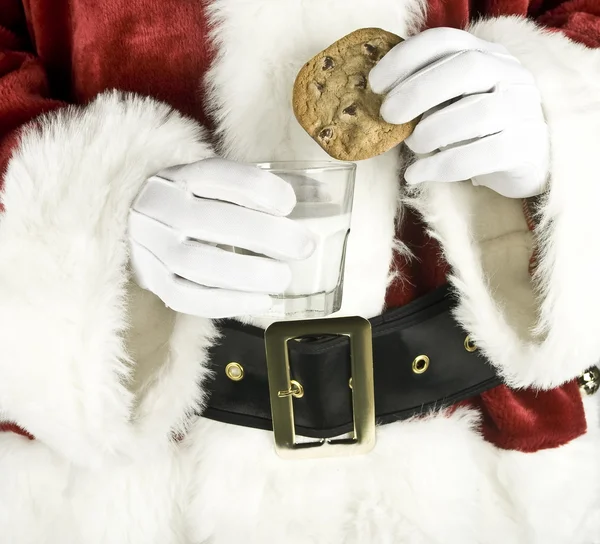 Weihnachtsmann hält Milch mit einem Schokoladenkeks in der Hand — Stockfoto