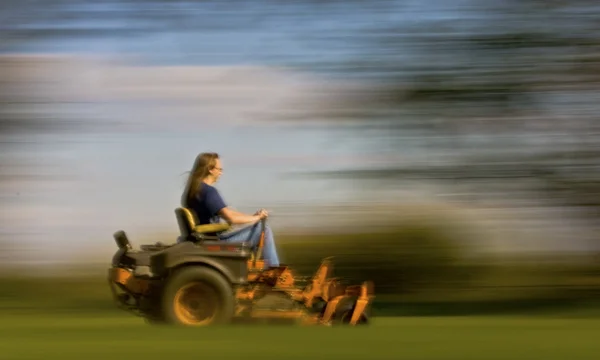 Macho cortando la hierba en el césped expansivo usando una segadora amarilla de giro cero — Foto de Stock