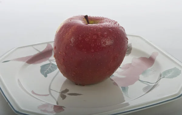 Bir plaka beyaz üzerine kırmızı elma — Stok fotoğraf