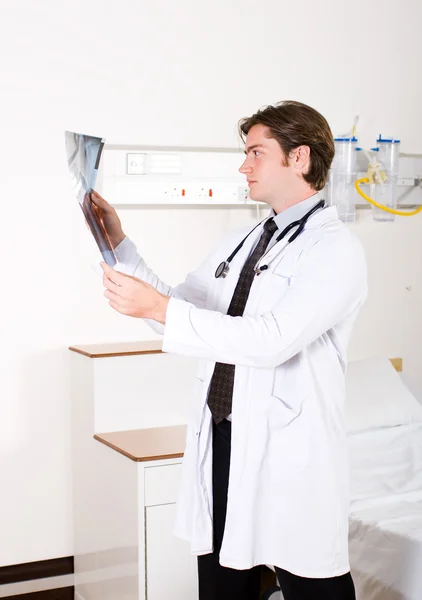 Genç erkek Doktor Röntgen hastane koğuşunda bakarak — Stok fotoğraf