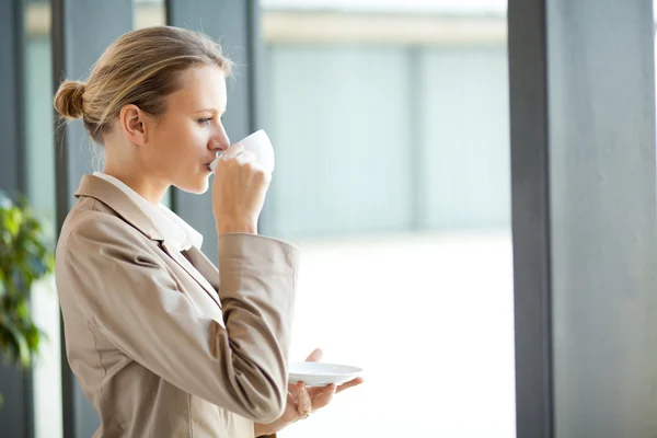 Hermosa joven empresaria bebiendo café en la oficina — Foto de Stock