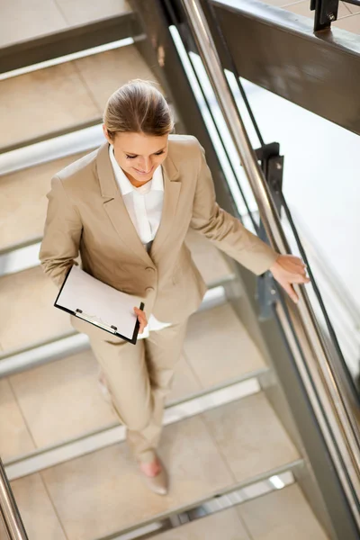 Attractive young businesswoman walking down stairs — Stock Photo, Image