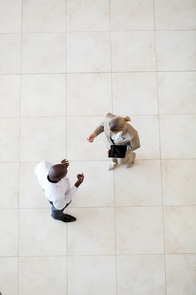 Gastos generales del hombre de negocios afroamericano hablando con la mujer de negocios en el vestíbulo — Foto de Stock