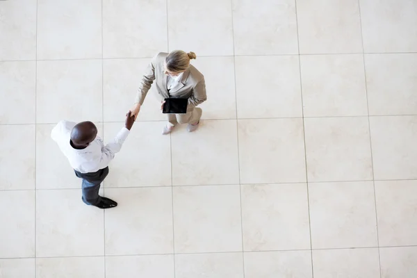 Empresario y mujer de negocios apretón de manos en el vestíbulo de la oficina — Foto de Stock