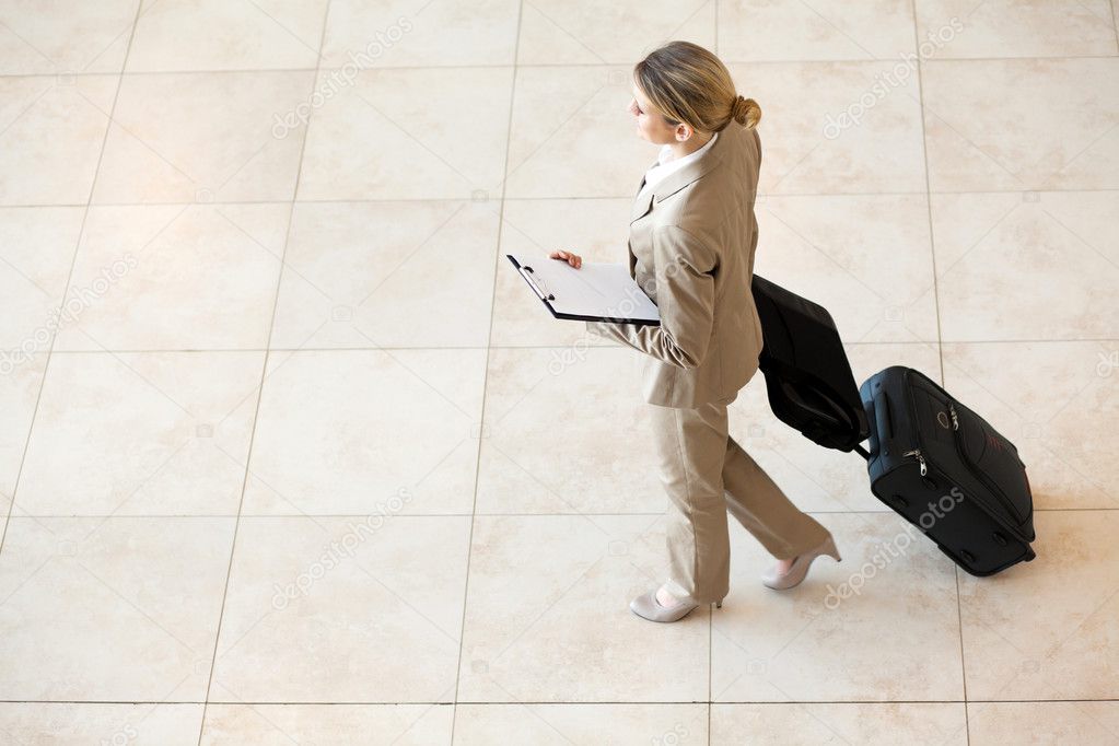 Young businesswoman walking at airport with luggage