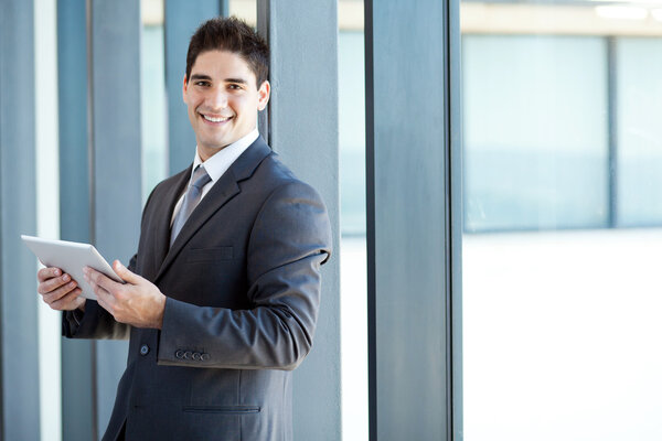 Happy young businessman with tablet computer in office