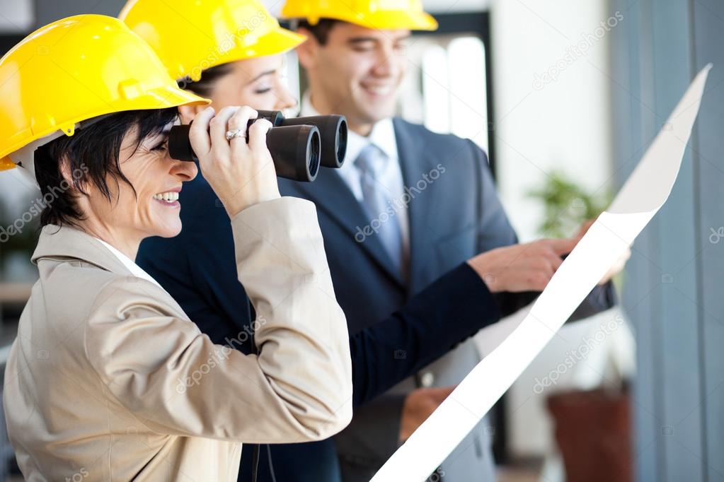 Project manager looking at construction site with binoculars
