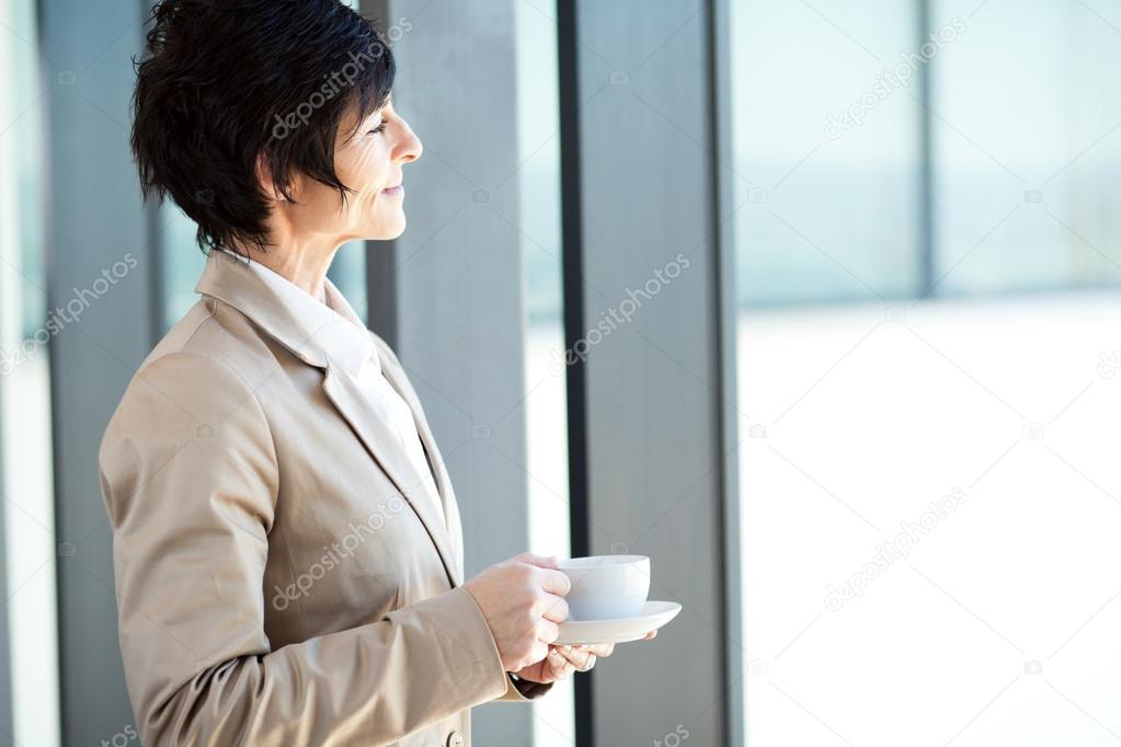 Smart middle aged businesswoman having coffee break