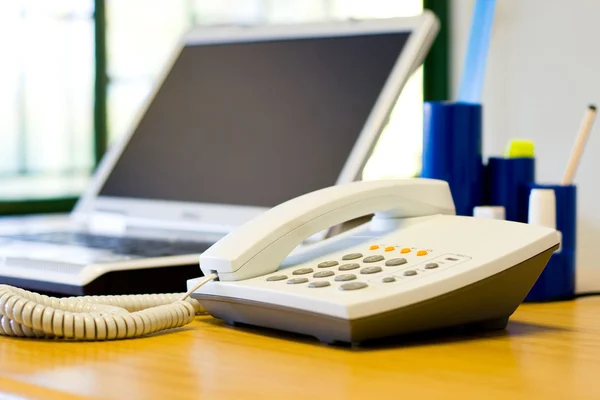 Skrivbord med telefon och laptop — Stockfoto