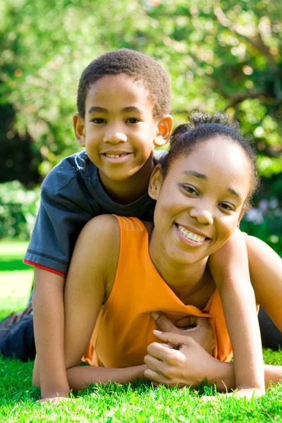 Afro-Amerikaanse moeder en zoon liggen op gras buitenshuis — Stockfoto