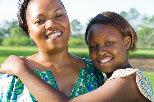 Счастливая африканская американская мать и дочь обнимаются на открытом воздухе — стоковое фото
