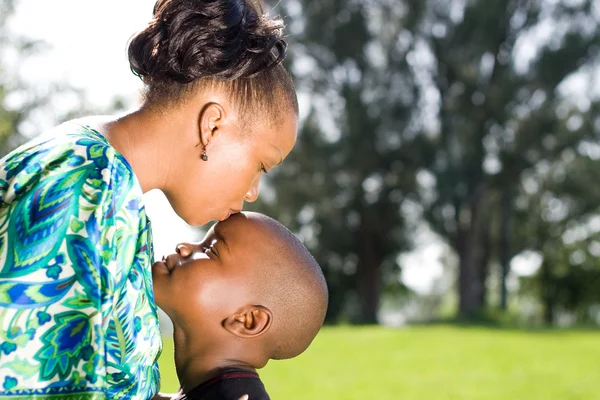 Mãe africana beijando filho ao ar livre — Fotografia de Stock