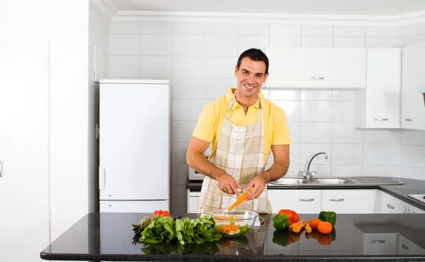 Joven hombre picando verduras en la cocina — Foto de Stock