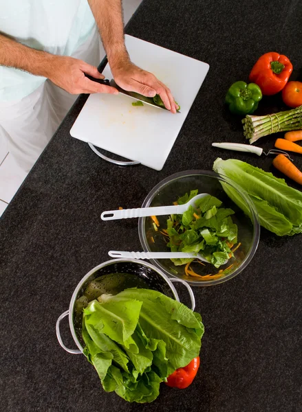 Jonge man hakken groenten in de keuken — Stockfoto