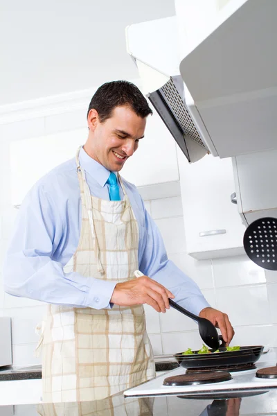 Jeune homme sauté légumes frits dans la cuisine — Photo