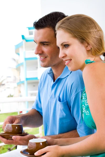 Szczęśliwa młoda para siedzi na balkonie picia kawy — Zdjęcie stockowe