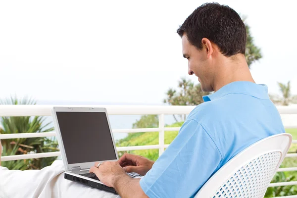 Hombre joven usando el ordenador portátil en balcón — Foto de Stock