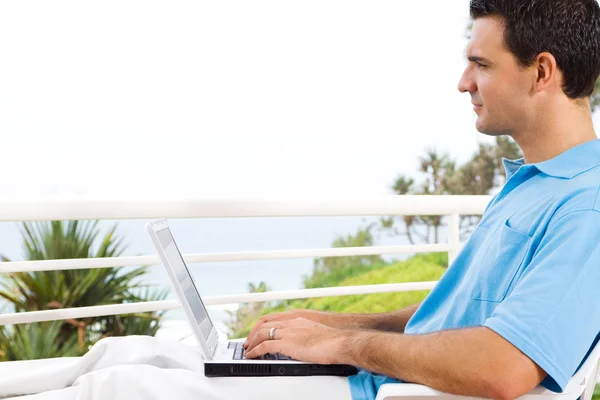 Junger Mann benutzt Laptop auf Balkon — Stockfoto