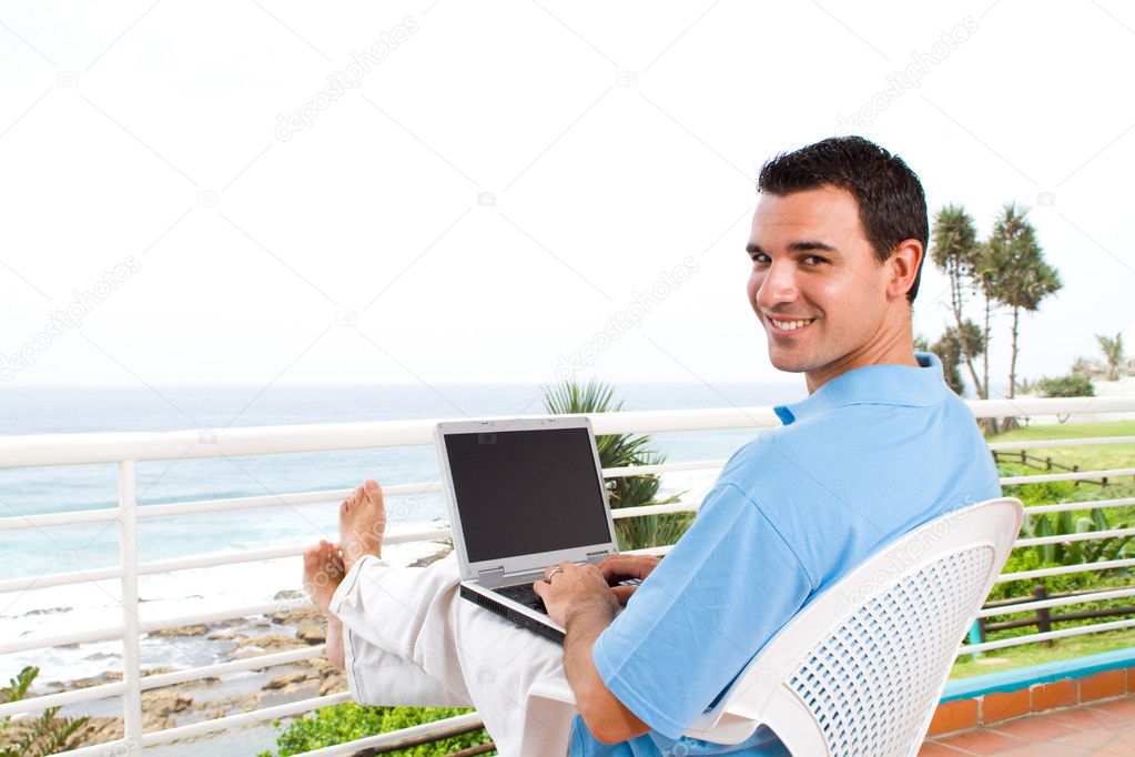 Young man using laptop on balcony