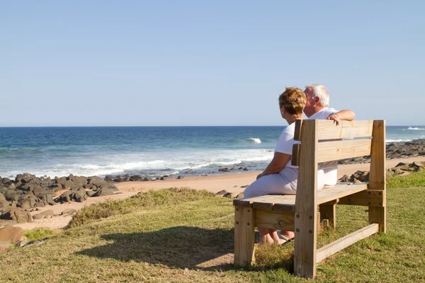 Ηλικιωμένο ζευγάρι κάθεται σε παγκάκι παραλία — Φωτογραφία Αρχείου