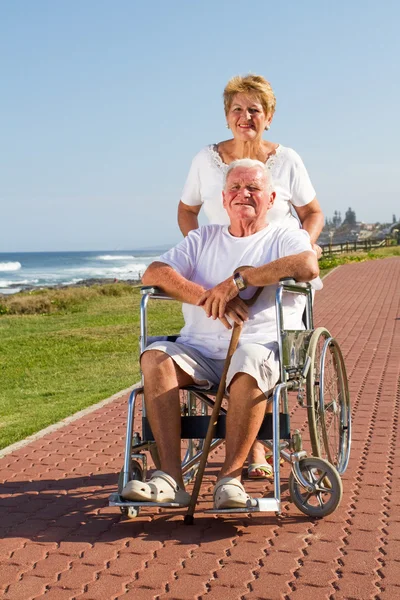 Szczęśliwa żona starszy mąż wypychanie na wózku inwalidzkim — Zdjęcie stockowe