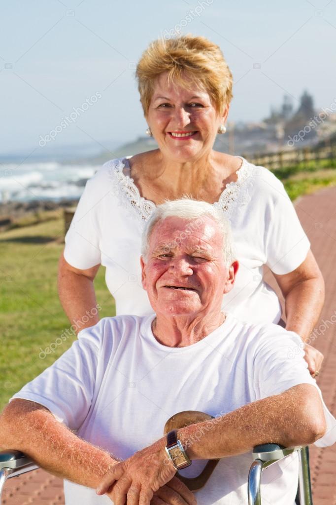 Senior man being pushed on wheelchair by his wife
