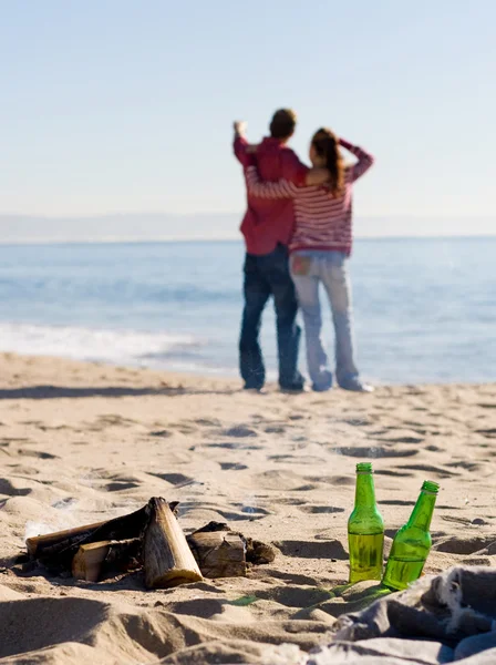 Młoda para relaks na plaży, skupić się na ognisku i piwo butelka — Zdjęcie stockowe