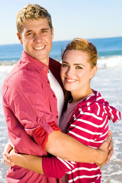 Νεαρό ζευγάρι αγκαλιάζει στην παραλία — Φωτογραφία Αρχείου